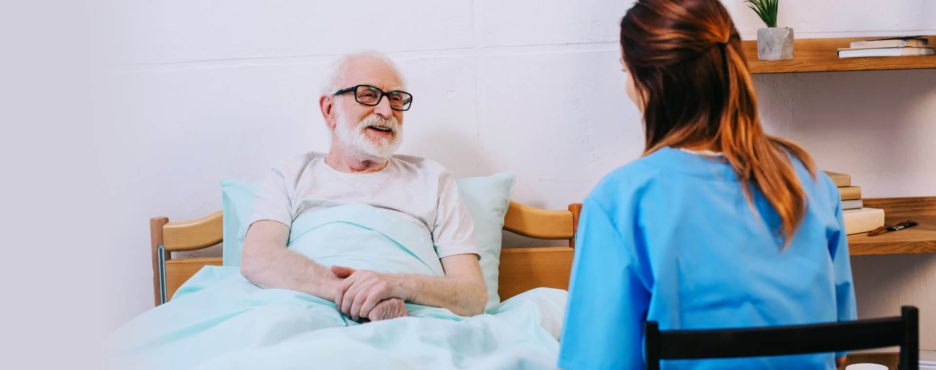 Old man on his bed talking to a caregiver