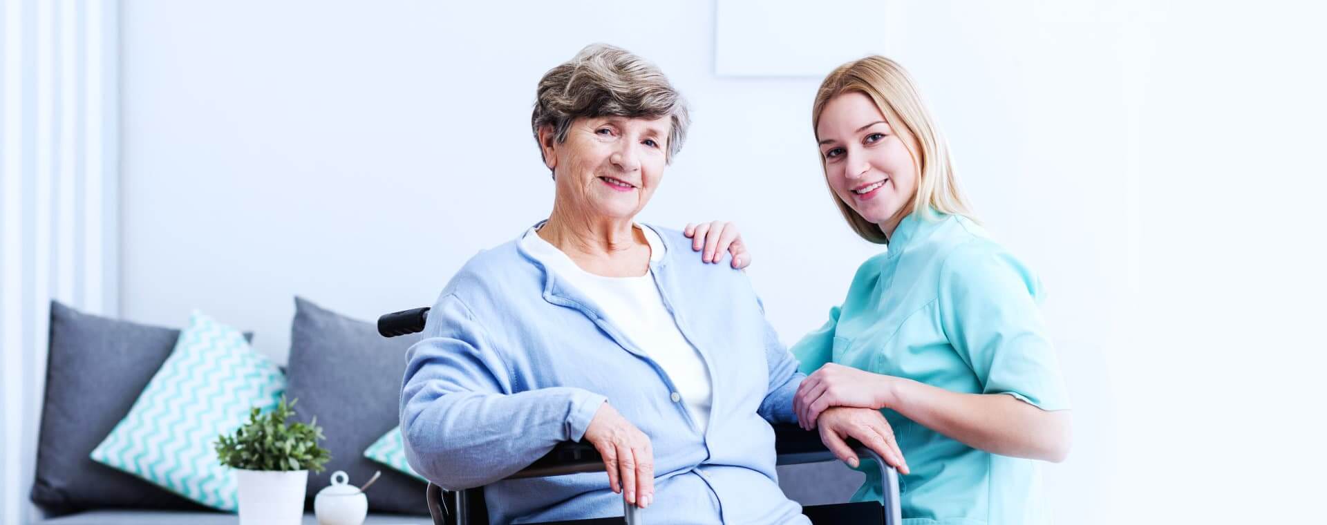 Caregiver holding the old womans hands while smiling