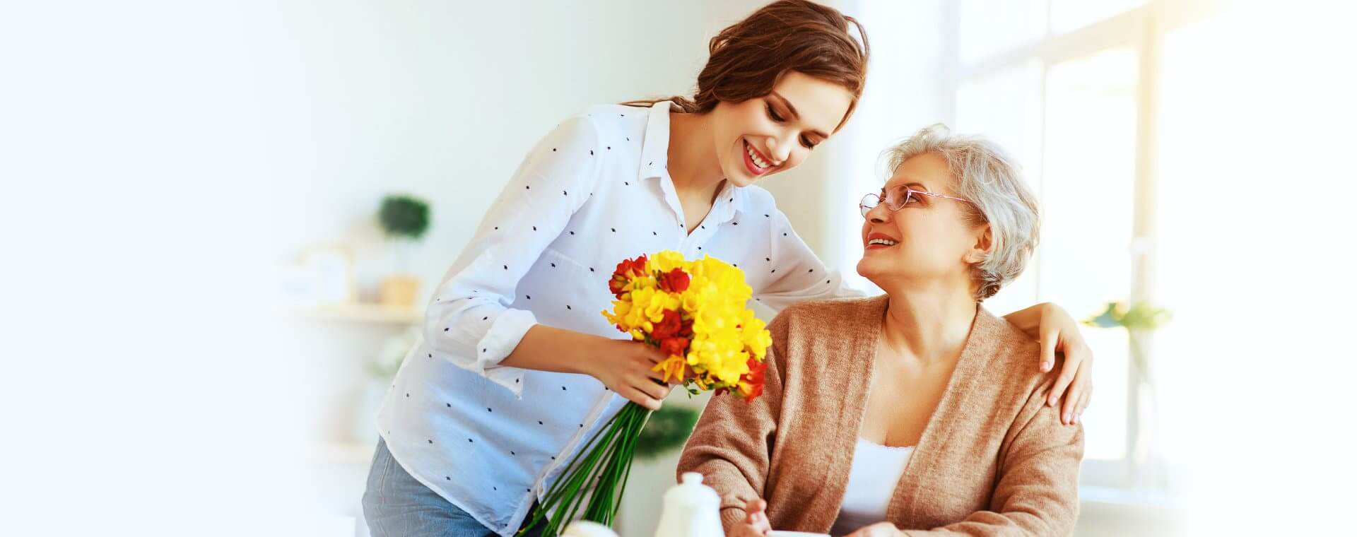 Woman giving flowers to an elderly woman